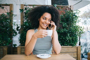 Cheerful ethnic woman on vacation in Barcelona using phone