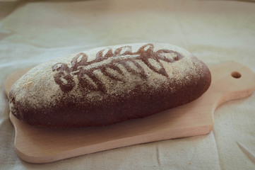 soft focus of loaf dark grain tasty bread with branch print and flour on wooden chopping board
