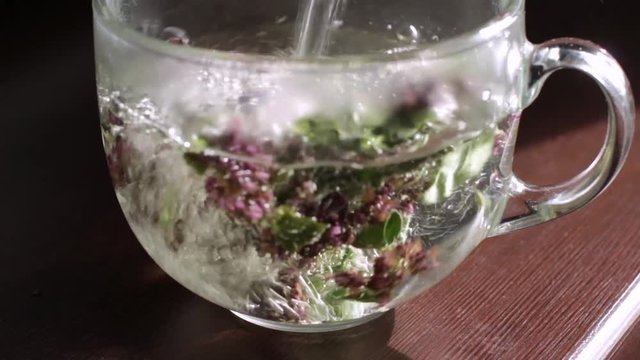 pouring hot water into a cup with herbs
