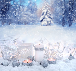 Fototapeta na wymiar Christmas decorative balls and candles on snow on a background the winter forest. Christmas or New Year greeting card.