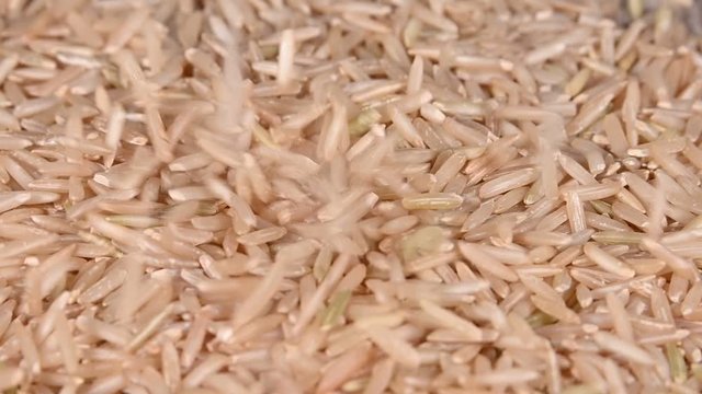 Close up brown rice falling on heap