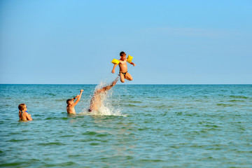 Children jump on the sea, family holidays with children on vacation. The father throws the child up in the water.