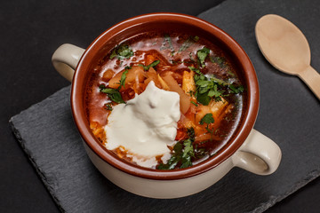 Ukrainian traditional borsch with wooden spoon on black background.