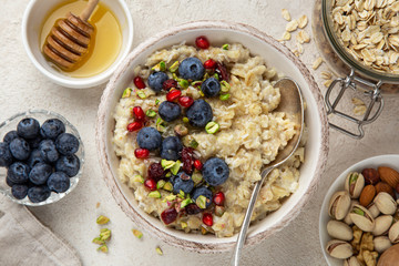 Oatmeal porridge with fresh berry, nuts and honey in bowl