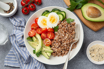 healthy vegan lunch bowl with avocado, egg, cucumber, tomato and buckwheat