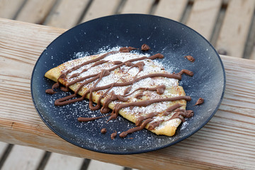 tasty chocolate crepes with sugar on a table
