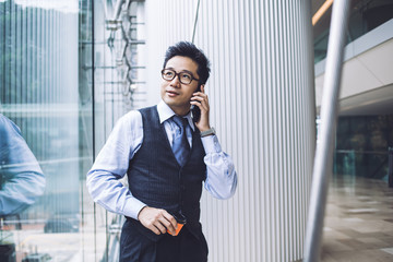 Inspired Asian businessman talking on smartphone in hall