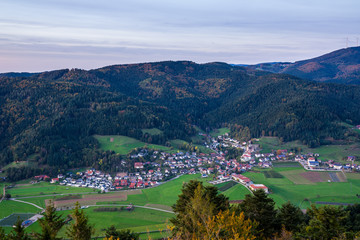 Fototapeta na wymiar Germany, Beautiful small black forest village fischerbach in kinzig valley surrounded by majestig forested mountains, aerial view above at sunset