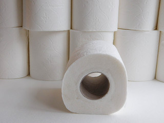 Rouleau de papier toilette vu de côté au premier plan et rouleaux superposés flous en arrière-plan