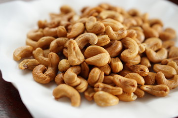 Close-up of fried cashew nuts in a dish with wood table.	