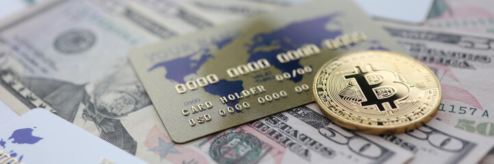 Gold coin bitcoin closeup lie on table with dollar paper and credit card aganist table background. Cryptocurrency exchange concept.