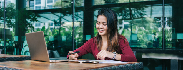 Smiling Asian woman working with papers in cafe