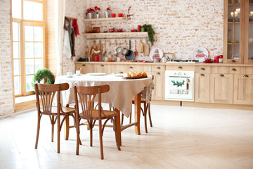 dining room in cottage style. Outdoor dining room interior with kitchen and brick walls. Stylish kitchen interior with wooden round table and chairs in rustic style. Cozy country house. Scandinavia