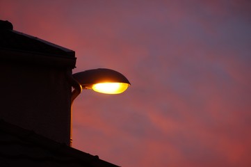 Street light with red sky on background. Lite Lamppost at sunset.