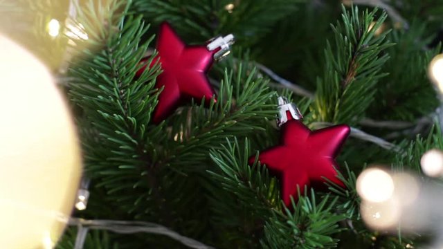 red star shaped christmas baubles and gold lights on christmas tree