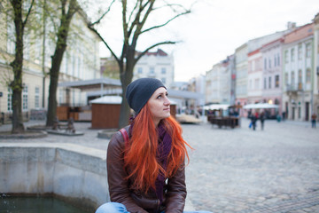 Red-haired girl in the town square at the fountain