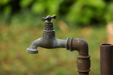 Exterior tap. Old tap with rusty pipe in garden.