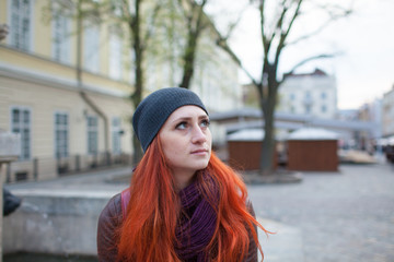 Red-haired girl in the town square at the fountain