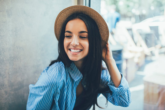 Beautiful female teenager with perfect toothy smile on face rejoicing during free time indoors feeling excited from expression emotions, prosperous Ukrainian hipster girl in stylish straw hat