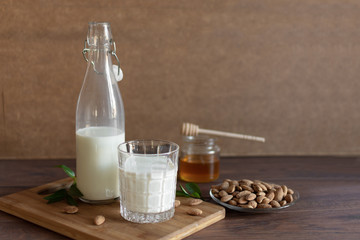 Fresh organic Almond milk in glass with almond nuts and honey. Healthy eating concept.