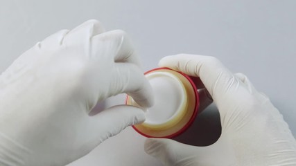 Cosmetologist in the Spa laboratory opens a jar of cream mask cosmetics.This video is about the effect of organic eco friendly cosmetics on human skin - Powered by Adobe