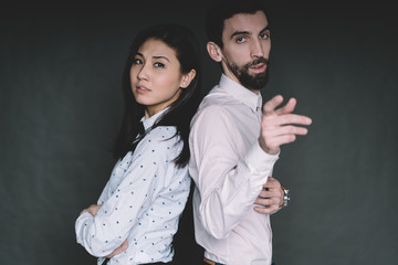 Young handsome man and pretty woman standing back to back posing in studio