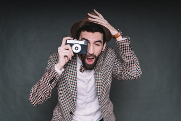 Surprised bearded hipster taking picture and holding hat