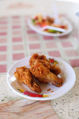 Crispy fried chicken Thai style serve on white plate have papaya salad background