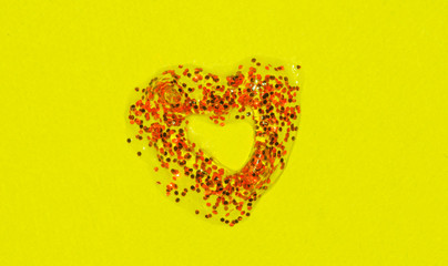 Red heart of spangles on a yellow background to the day of Saint Valentine.