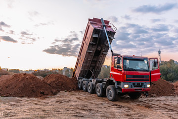 A dump truck is dumping gravel on an excavation site