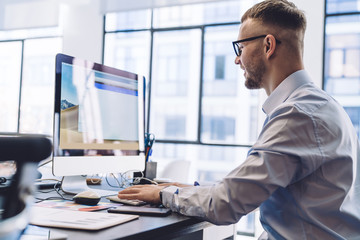 Fototapeta premium Cheerful adult male worker working on PC in office