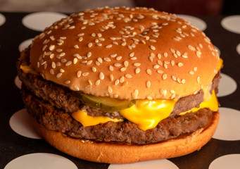 large cheeseburger with cream cheese, pickles and two large patties