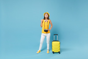 Traveler tourist woman in yellow casual clothes, hat with suitcase photo camera isolated on blue background. Female passenger traveling abroad to travel on weekends getaway. Air flight journey concept