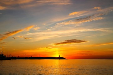 Naklejka na ściany i meble Sunrise in Malaga, Spain. Lighthouse on the horizon