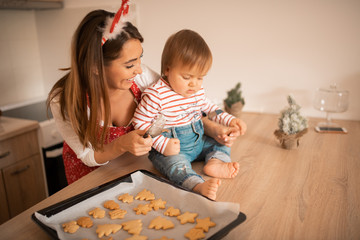 A young mom and a child in the kitchen with cookies.