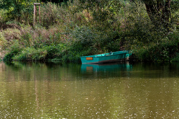  50/5000 small wooden green rowing boat near river among trees