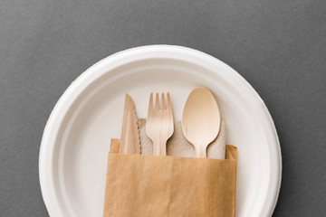 cutlery, recycling and eco friendly concept - set of wooden spoon, fork and knife on paper plate on...