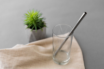 eco friendly concept - empty glass mug of with reusable metallic straw