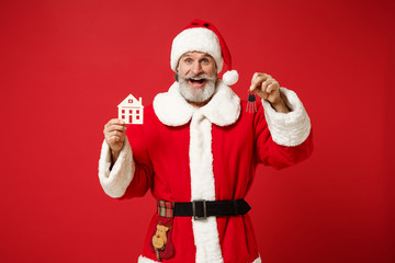 Fototapeta na wymiar Excited elderly gray-haired mustache bearded Santa man in Christmas hat posing isolated on red background. New Year 2020 celebration holiday concept. Mock up copy space. Hold house and bunch of keys.