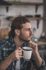 Thoughtful romantic man having a cup of coffee