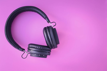 Portable black headphones on pink background. Mock-up with text space. Layout, creative design, bright frame. Music lifestyle. Youth earphones.