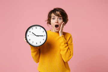 Shocked young brunette woman girl in yellow sweater posing isolated on pastel pink wall background....