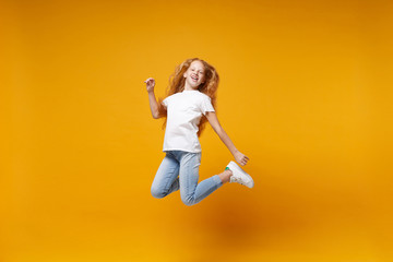 Cheerful little ginger kid girl 12-13 years old in white t-shirt isolated on yellow background...