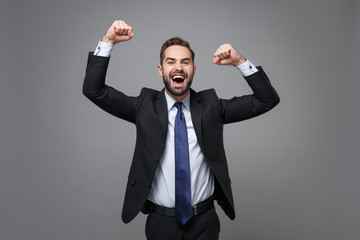 Happy young business man in classic black suit shirt tie posing isolated on grey wall background in...