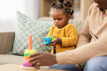 family, parenthood and people concept - african american father and baby daughter playing with toy...