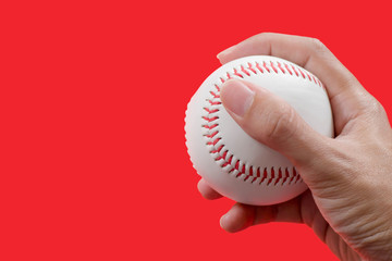 Hand holding baseball on red background