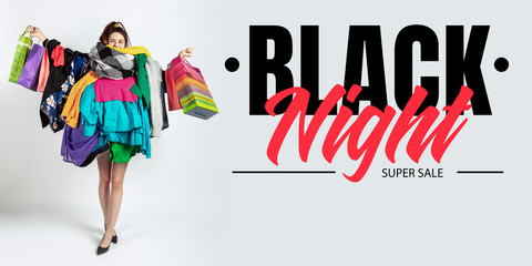 Black night, finance concept. Woman addicted of sales and clothes. Female model wearing too much colorful clothes. Fashion, style, black friday, sale, purchases, money, online buying. Flyer for ad.