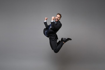 Happy young business man in classic black suit shirt tie posing isolated on grey background....