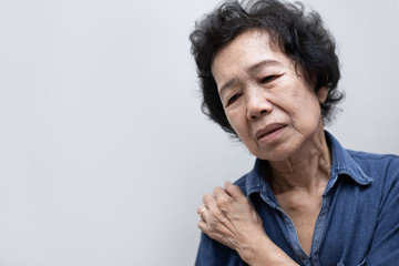 Elderly Asian woman put her hand on his shoulder because of shoulder pain or muscle pain. Healthcare and Medical concept.