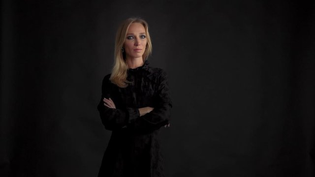 woman alone in studio wears a black dress on black background. Evening makeup look